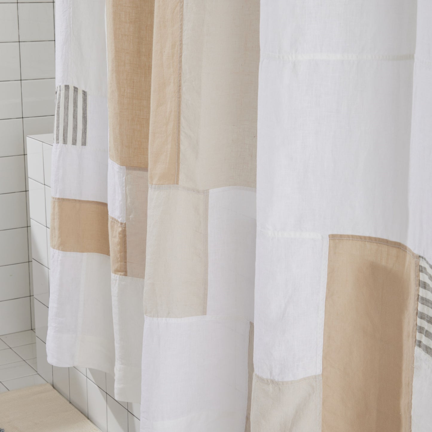 Close up detail of beige and cream multi-color linen shower curtain showing patchwork design.