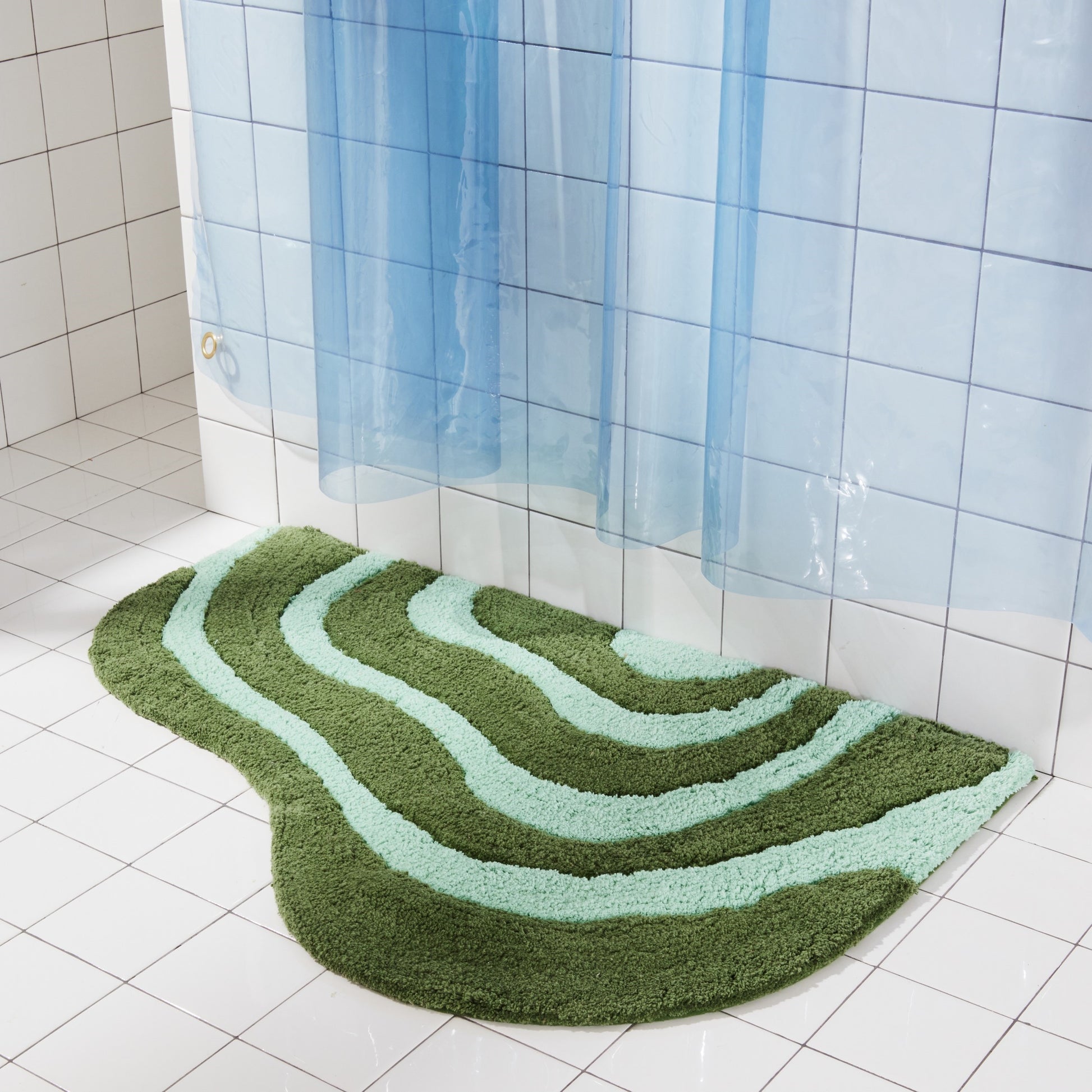 Jade and pine bath mat in 21"x31" size sitting next to white tiled bathtub styled with sun shower in atlantic. 