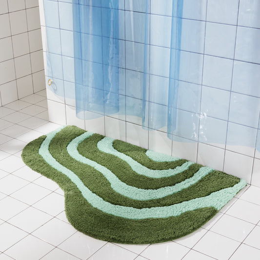 Jade and pine bath mat in 21"x31" size sitting next to white tiled bathtub styled with sun shower in atlantic. 