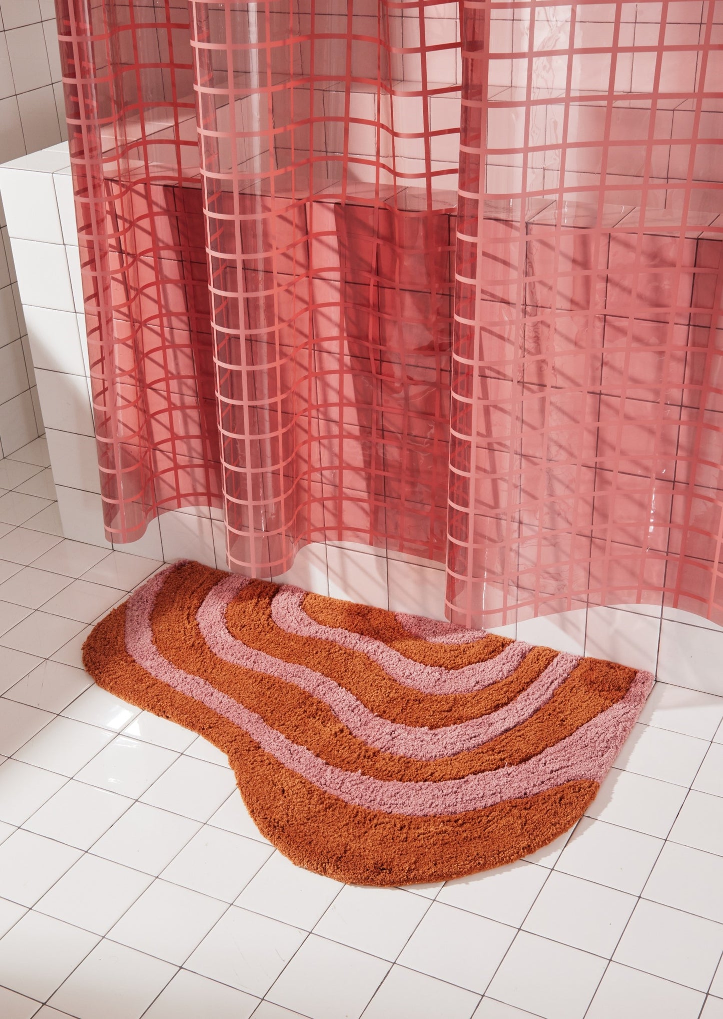 Honey and rose bath mat in 21"x31" size sitting next to white tiled bathtub styled with 2x2 sun shower in rose. 