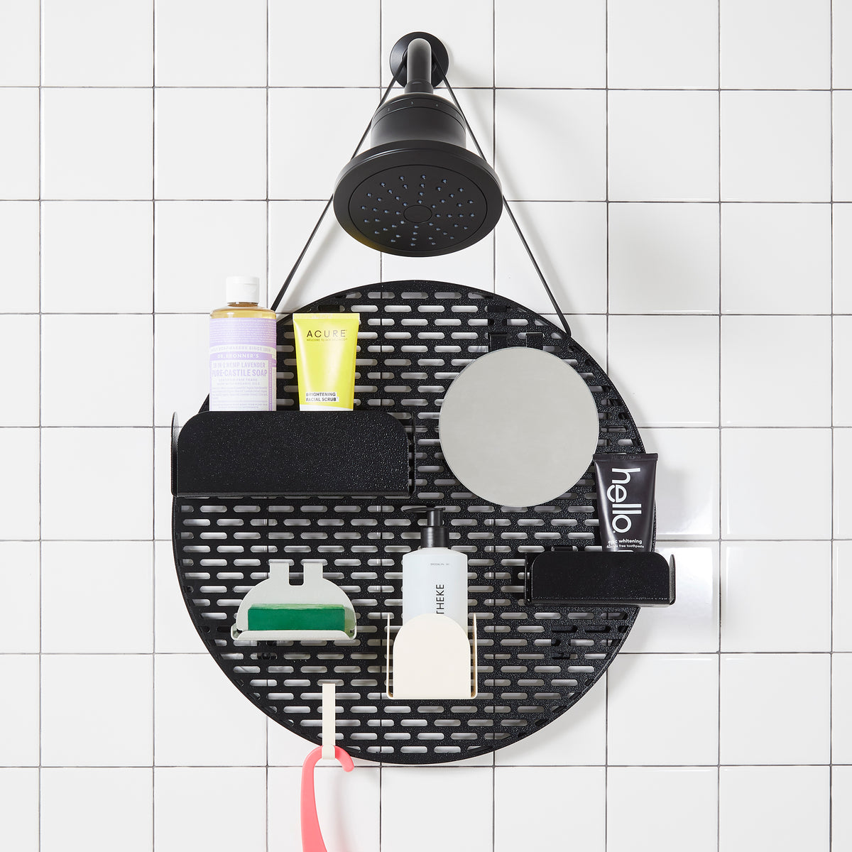 The spot modular shower organizer with shelving pieces arranged and holding products, hanging in a white tiled shower.